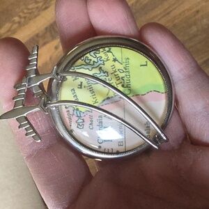 Vintage kitsch travel brooch featuring planes flying over a map